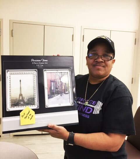 Andrea holding a donated picture frame that now hangs in her apartment.